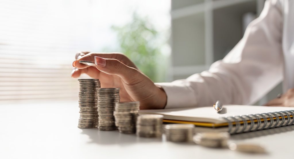 A woman stacking quarters in successively larger piles all in a straight line.