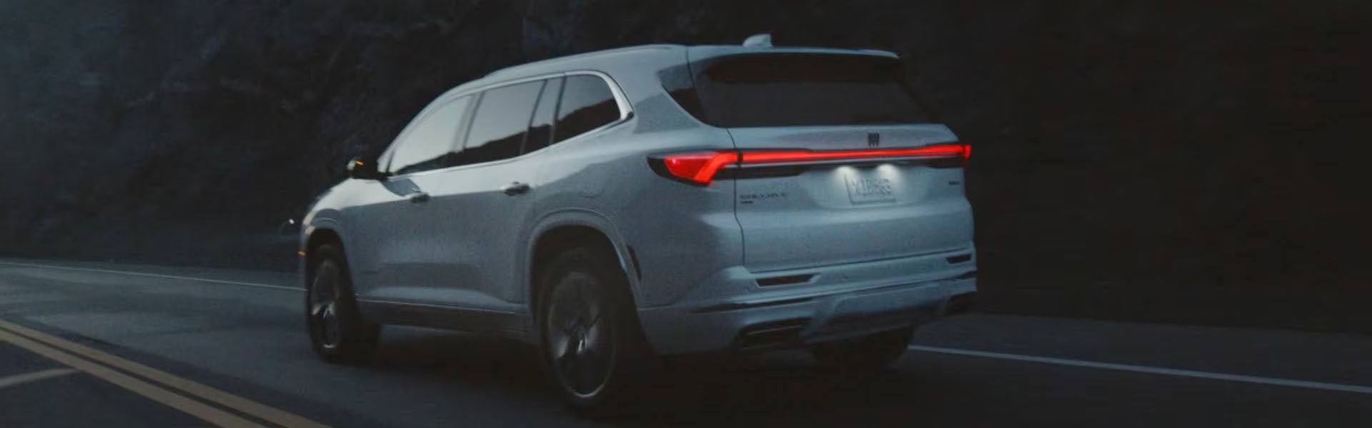 White 2026 Buick Enclave driving along a coastal road