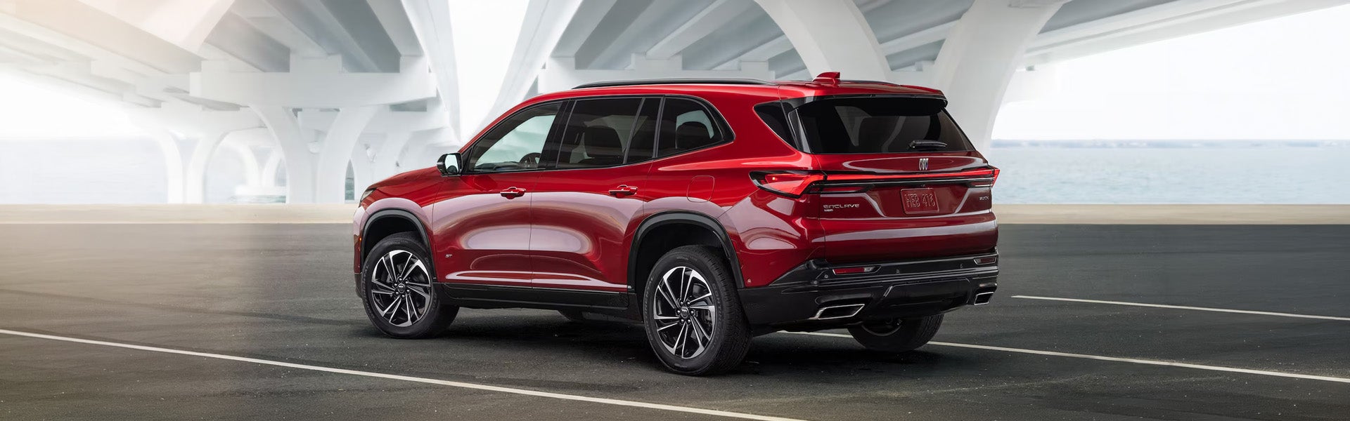 Red Buick Enclave parked under a modern white bridge structure